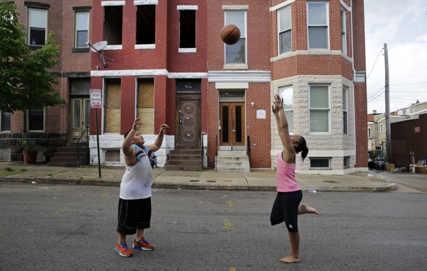 Children play with a basketball in front of a vacant home, left, and a restored home in the Reservoir Hill neighborhood of Baltimore on May 10, 2015. (AP Photo/Patrick Semansky)